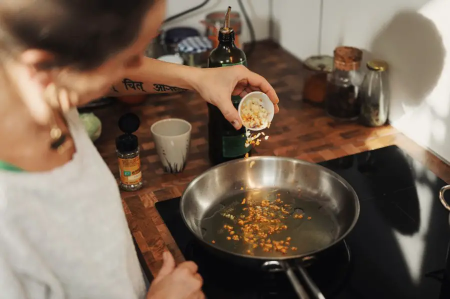A woman adding garlic to a pan
