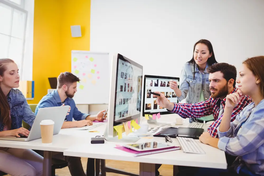 Businessman-showing-computer-screen-to-coworkers-in-creative-office (1)