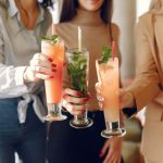 elegant-women-standing-cafe-drinking-cocktails-min