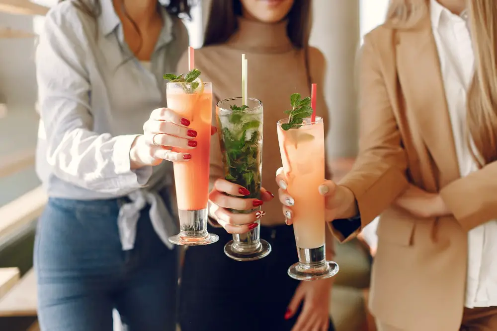 elegant-women-standing-cafe-drinking-cocktails-min