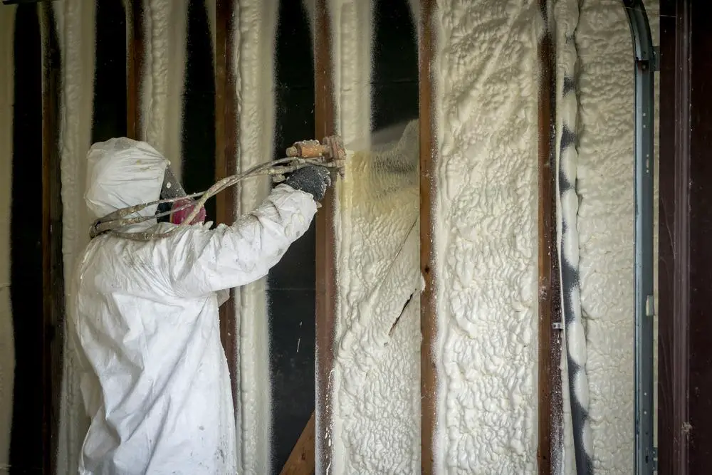 A man is spraying Foam Insulation a home