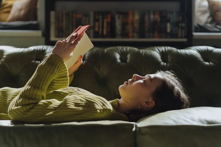 Person on the couch, holding a fiction book to read