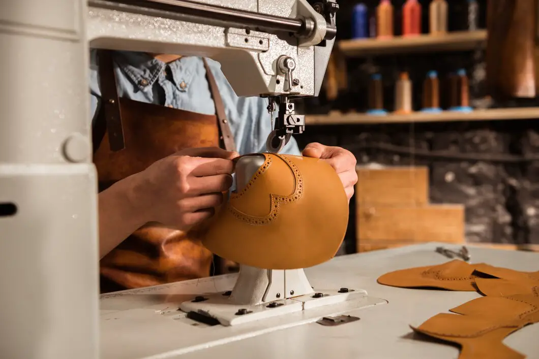 close-up-shoemaker-using-sewing-machine_171337-12309