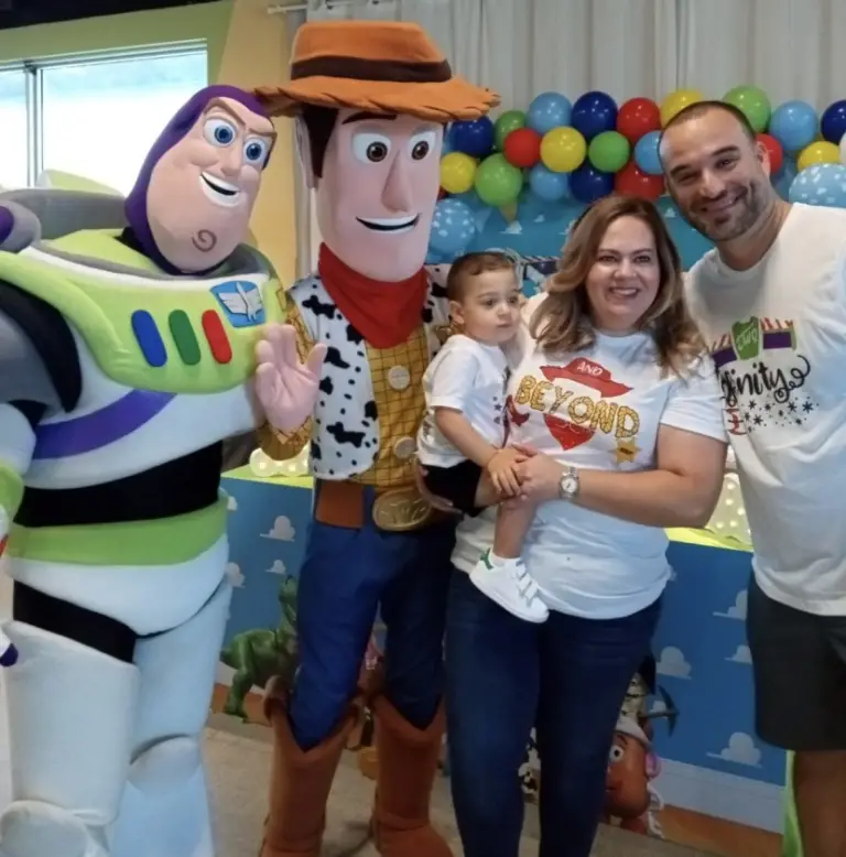 An image of a couple with their baby posing with Toy Story characters   