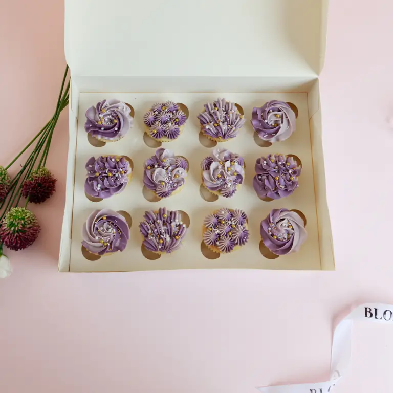 A box of lavender and lilac cupcakes for a birthday.