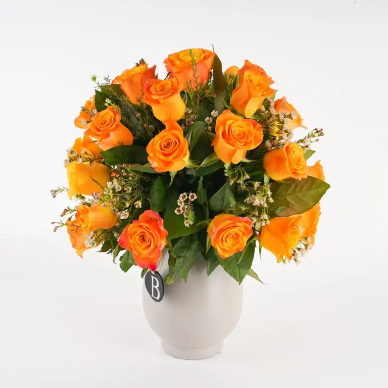 A vase of orange roses that are perfect for a birthday party.