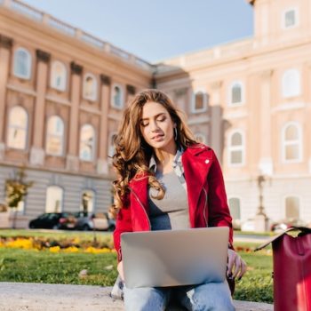 outdoor-portrait-serious-curly-female-student-sitting-with-laptop-ground_197531-6965 (1)