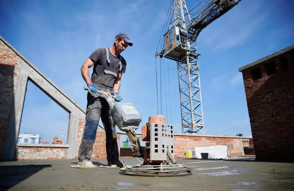 A man worker leveling fresh floor with special machine