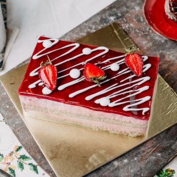 square-cake-cream-designed-red-strawberry-sliced-along-with-hot-tea-grey-desk_140725-15276