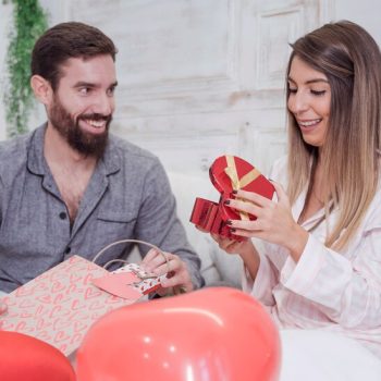young-couple-sitting-bed-with-gifts_23-2148012271